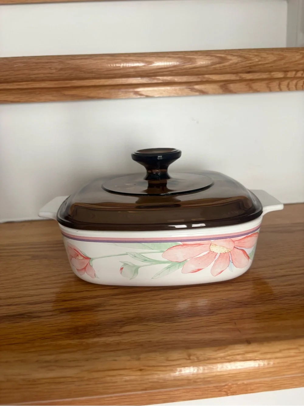 A vintage Corning Ware casserole dish in the Peony Floral pattern with lid